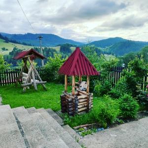 ein kleines Haus mit rotem Dach und einem Holzhaufen in der Unterkunft Bucovina mea in Breaza