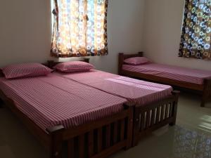 duas camas num quarto com lençóis roxos em Shantham Service Apartments, Kinathukadavu, Coimbatore em Coimbatore