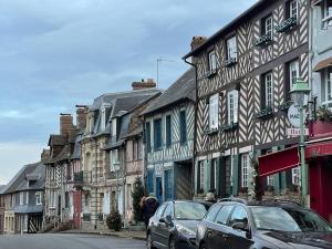 a row of buildings with cars parked on a street at La petite maison dans la vallée d Auge in Saint-Étienne-la-Thillaye