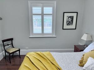 a bedroom with a bed and a chair and a window at Penzance Cottage in Adelaide