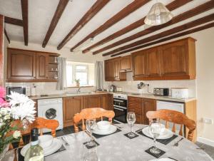 a kitchen with wooden cabinets and a table with chairs at Bwthyn Derwin Fawr in Dolbenmaen