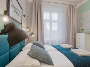 1 dormitorio con 1 cama con cabecero azul y ventana en OK KRAK Apartments, en Cracovia