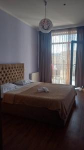 a bedroom with a large bed and a large window at Natia rooms in Tbilisi City