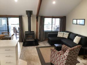 a living room with a black couch and a wood stove at Strath Creek Station farm-stay in Strath Creek
