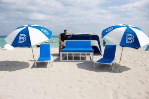 a man sitting in front of a tent on the beach at 4 RM on Beach SoBeSuites by AmericanVacationLiving in Miami Beach