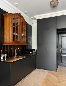 una cocina con armarios negros y fregadero en Supreme Apartment en Cracovia