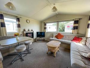 sala de estar con sofá, mesa y TV en Lovely 6 Berth Caravan With Decking, Close To The Beach In Suffolk Ref 68075bs en Lowestoft