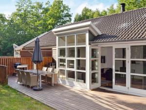 une terrasse avec une véranda dotée d'une table et d'un parasol dans l'établissement 10 person holiday home in Hasle, à Hasle