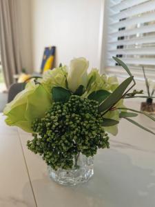 a glass vase filled with green flowers on a table at Paradise Retreat in Tauranga
