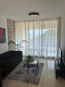 a living room with a black couch and a table at Daissy house - דירה פרטית בנאות גולף in Caesarea