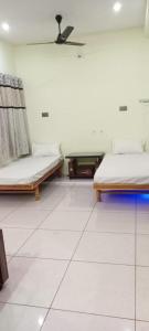 two beds in a room with white tile floors at Shaury Homestay in Garudeshwar +4 photos