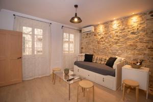 Una sala de estar con un sofá y una pared de piedra. en The Monastery Apartment, en Corfú