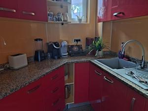 a kitchen with red cabinets and a sink at Vila Ambient frontal la mare in Mamaia Sat/Năvodari +25 photos