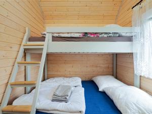 two bunk beds in a wooden room with a ladder at Domki Malibu in Rusinowo