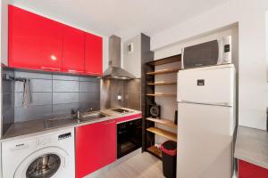 een keuken met rode kasten en een wasmachine bij Aka Appart'Hotel " Le Petit Coin de Lavaur" in Lavaur +1 foto