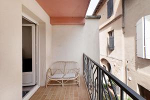 una silla de mimbre sentada en el balcón de un edificio en Aka Appart'Hotel " Le Petit Coin de Lavaur", en Lavaur