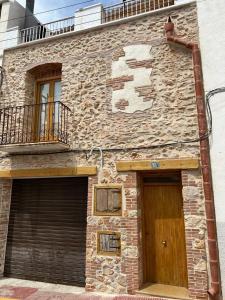Edificio de piedra con puerta y balcón en Casa Vicent, en Alcanar