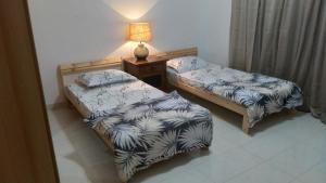 two beds in a room with a lamp on a table at Baran Homestay in Muscat