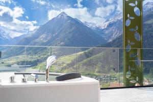 y baño con bañera y vistas a las montañas. en Oliven- & Genusshotel Hirzer, en Scena