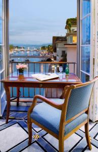 einen Tisch und einen Stuhl auf einem Balkon mit Blick auf das Wasser in der Unterkunft Storchen Zürich - Lifestyle boutique Hotel in Zürich