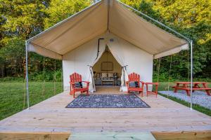 a tent with two red chairs and a table at Heated Glamping Tent in Cassville