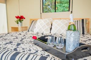 a tray with a bottle of wine and glasses on a bed at Heated Glamping Tent in Cassville