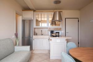 a kitchen with white cabinets and a wooden table at Zefiro Apartments in San Vincenzo