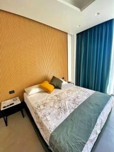 a bedroom with a large bed with blue curtains at Hotel Portum in Giardini Naxos +70 photos