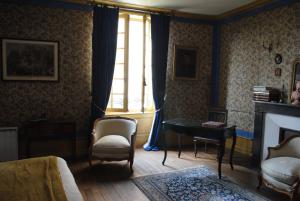 uma sala de estar com lareira e uma mesa e cadeiras em Le Ragois em Richelieu