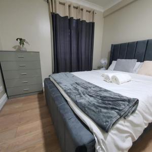 sypialnia z dużym łóżkiem i komodą w obiekcie Bungalow in leafy area w mieście Upminster