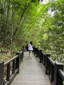 een vrouw die op een houten brug in een bos loopt bij 蓬萊生態農場仙山民宿 in Nanzhuang