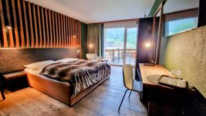a bedroom with a bed and a desk and a window at Amber Ski-in/out Hotel & Spa in Saas-Fee