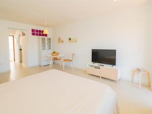 een witte slaapkamer met een bed en een televisie bij Cubo's Fuengirola Leisure Port in Fuengirola