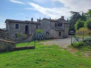 uma velha casa de pedra com um portão num quintal em Podere Leporino em Sarteano