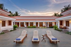 a courtyard with lounge chairs and a building at Leoney Resort Goa in Vagator