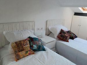 Habitación blanca con 2 camas con almohadas en Coro, en Villaviciosa