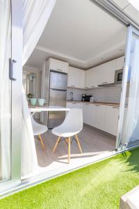 ラ・プラヤ・デ・アルグイネグインにあるCozy and sea views private terrace apartmentの白いキャビネット、テーブルと椅子付きのキッチンが備わります。