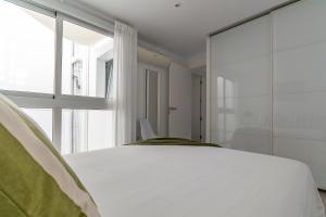 une chambre avec un lit blanc et une grande fenêtre dans l'établissement Amplio apartamento recién reformado, à Playa de Arguineguín