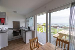 a kitchen with a dining table and a balcony at Lundy Sea View Villa - Mobility friendly in Bideford