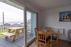 ein Esszimmer mit einem Holztisch und einem Balkon in der Unterkunft Lundy Sea View Villa - Mobility friendly in Bideford