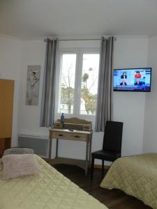 a bedroom with a desk and a window with a television at Hotel Jersey in Barneville-Carteret