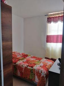 a bedroom with a bed with a red and white quilt at Apartamento Jonas in Ibagué