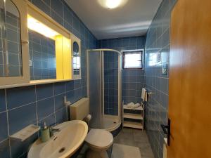 La salle de bains est pourvue de carrelage bleu, de toilettes et d'un lavabo. dans l'établissement Apartmani Rahela, à Vodice