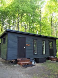 a black tiny house parked in the woods at LevonMajat in Joensuu