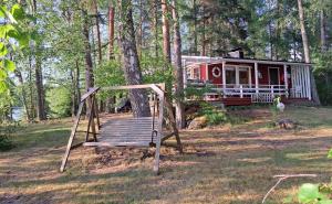 a swing set in front of a tiny house at Lakeside Lea, rantamökki 