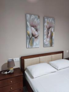 Sea View Apartments Poseidon في ليبتوكاريا: سريرين في غرفة نوم مع صورتين على الحائط