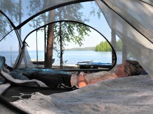 a woman laying in a tent near the water at LevonMajat in Joensuu