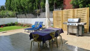 patio ze stołem, krzesłami i sprzętem do grillowania w obiekcie Villa Bettina w mieście Sarroch