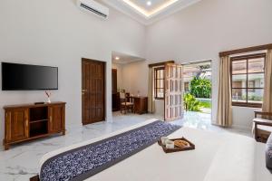 una sala de estar con TV de pantalla plana y una habitación en Leoney Resort Goa, en Vagator