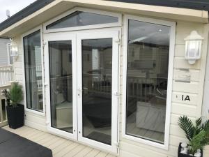 a conservatory with glass doors on a house at Hot Tub Accommodation North Wales Caravan in Rhyl